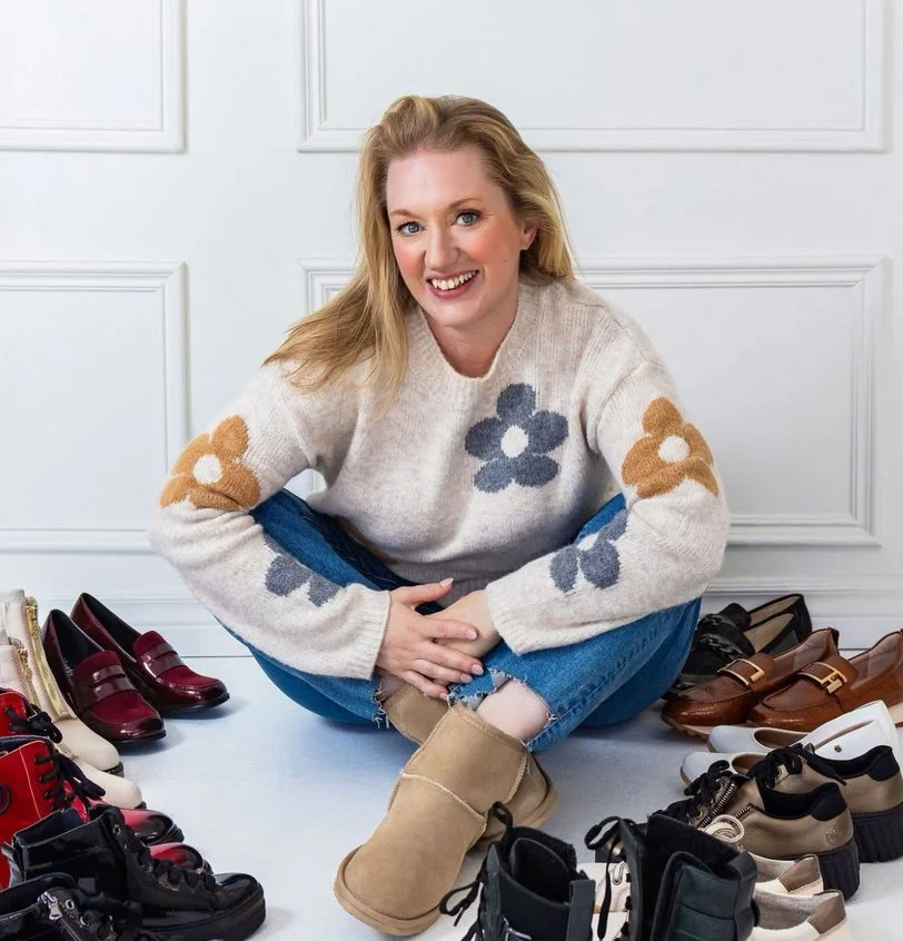 Claudine Péclet, propriétaire d’Escarpins et Vilebrequins, assise parmi les bottes et les chaussures de sa boutique.