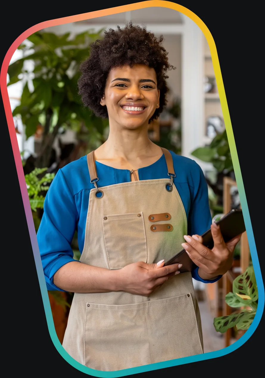 Une propriétaire de petite entreprise en tablier, une tablette à la main, dans sa boutique.